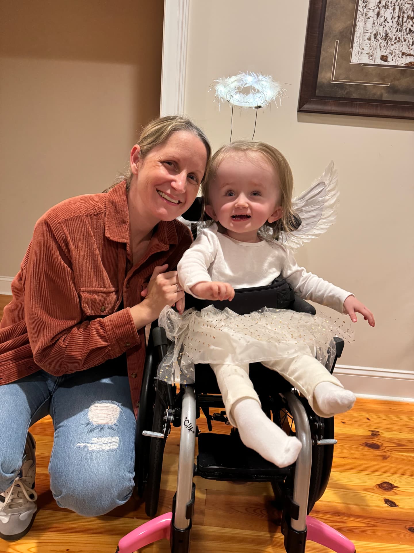 Harlow dressed as an angel with wings and a halo, beside her mom