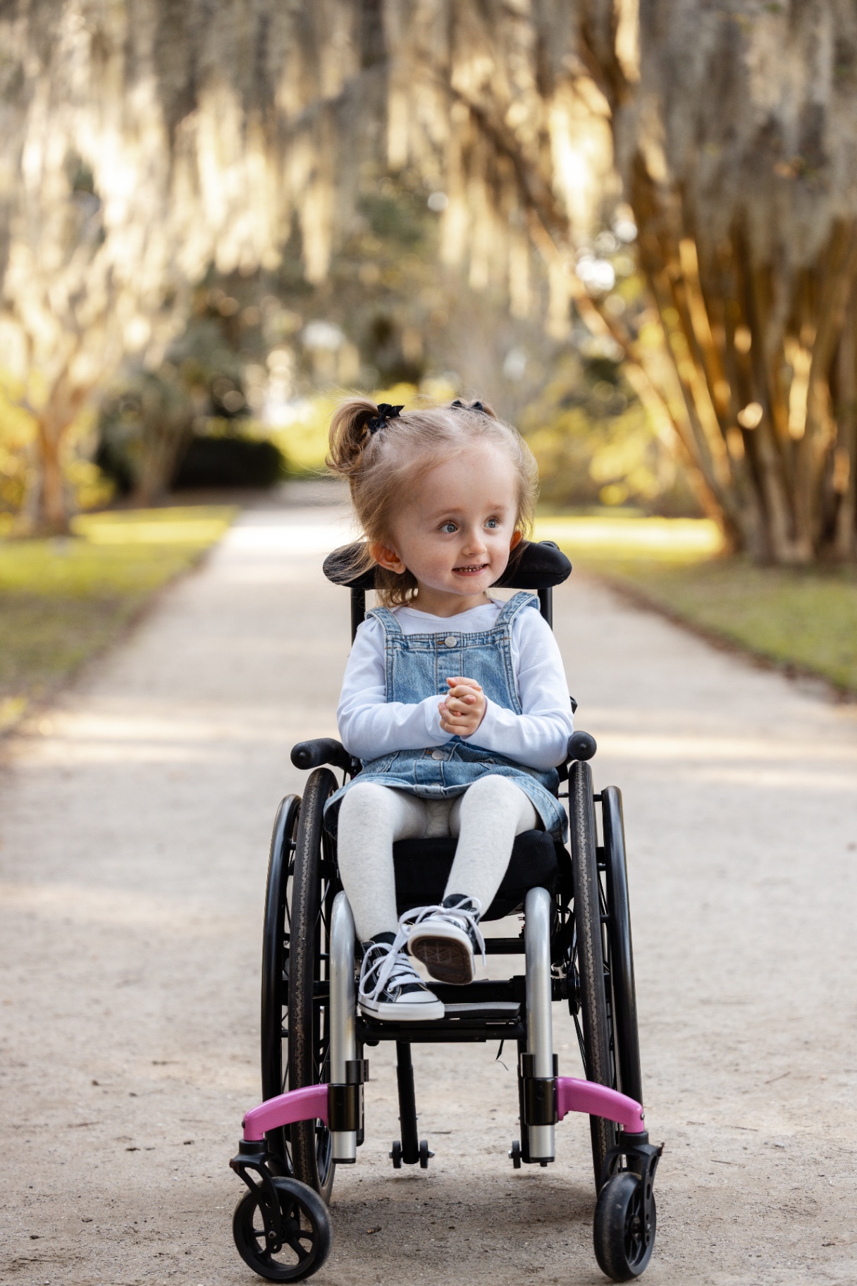 Harlow, a smiling little girl in her wheelchair