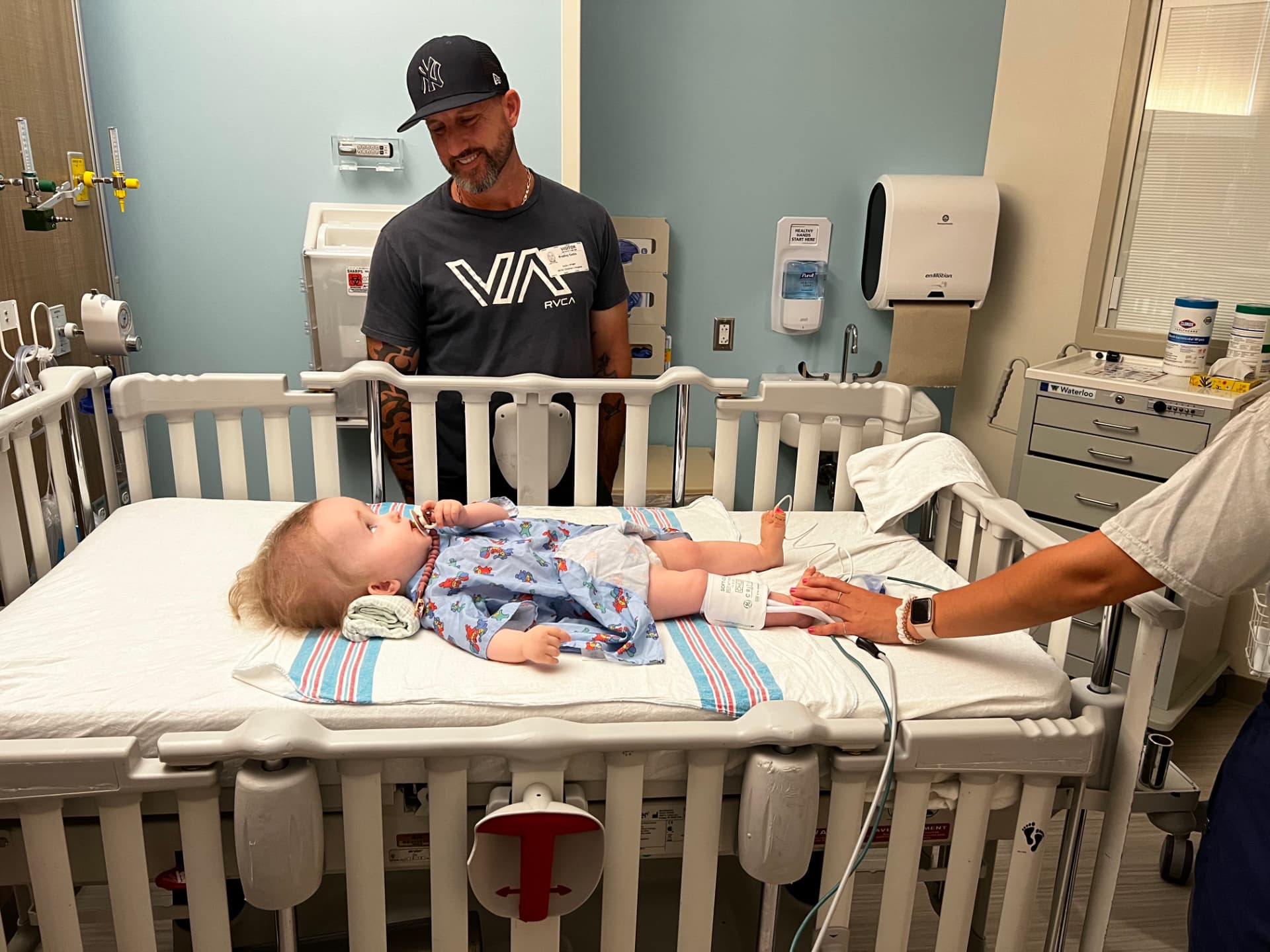 Brad smiling beside Harlow's hospital crib