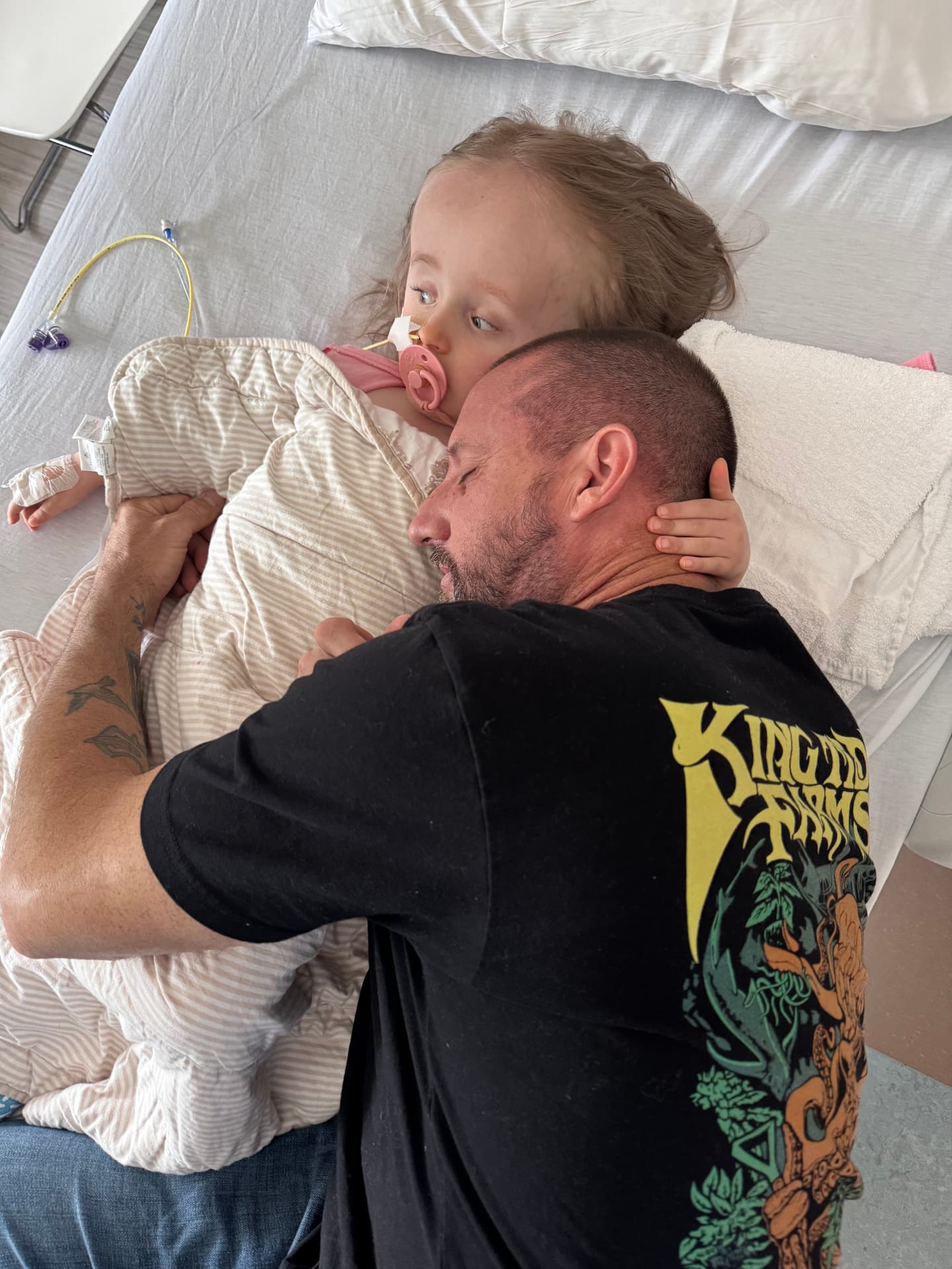 Brad cuddling Harlow in her hospital bed