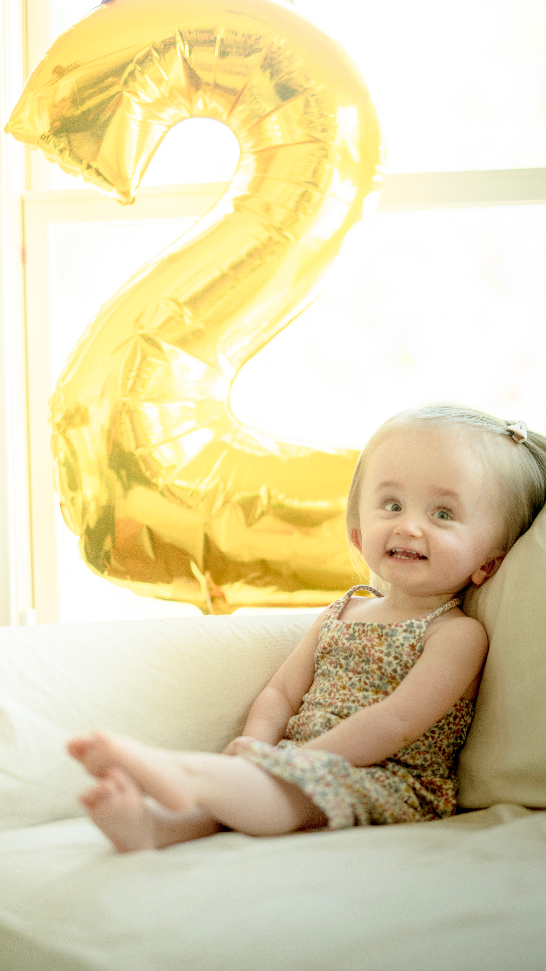 Toddler Harlow beside a gold '2' balloon