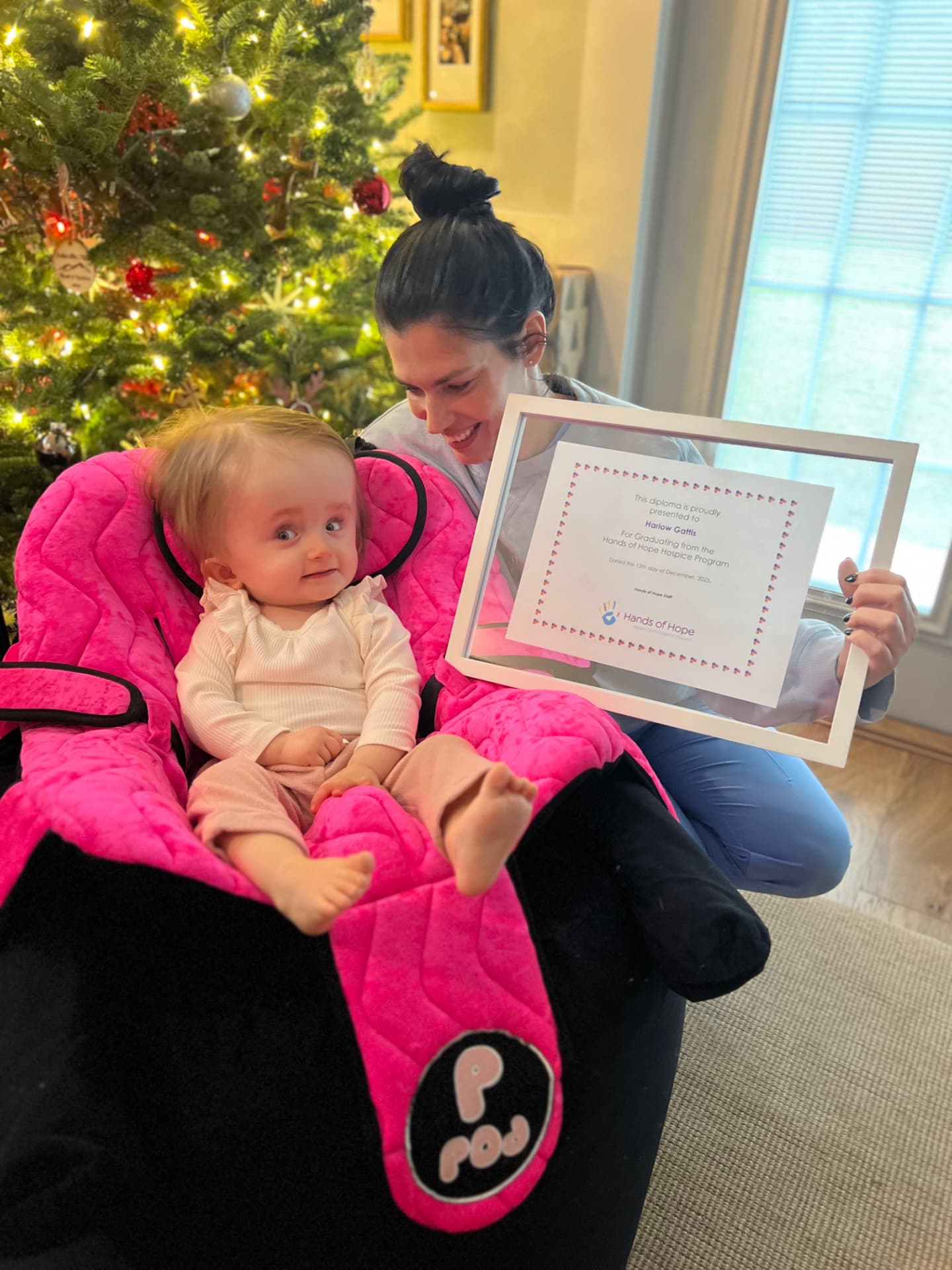 Harlow with her hospice graduation diploma by the Christmas tree